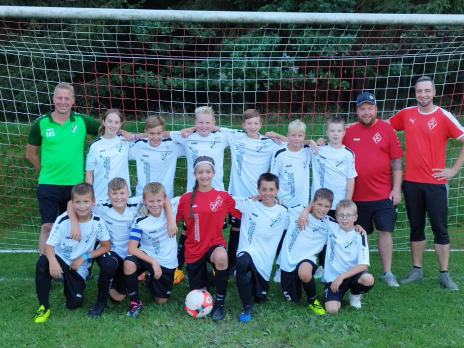 Fußballspieler im Zweikampf, im Hintergrund noch mehr Spieler und Zuschauer